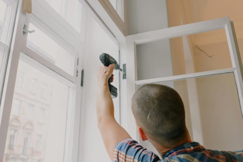 pexels photo 5691503 5691503 A handyman works with a drill installing window hinges indoors.